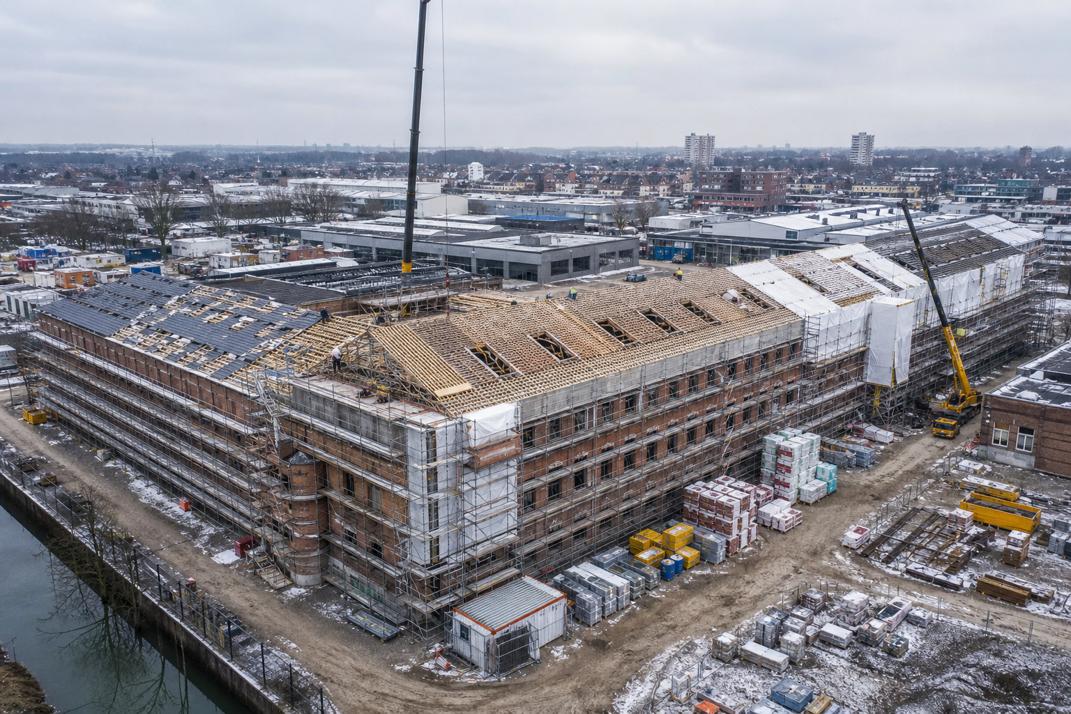 Grote renovatiewerf in winterfase met kraan en duidelijk afgebakende werkzones